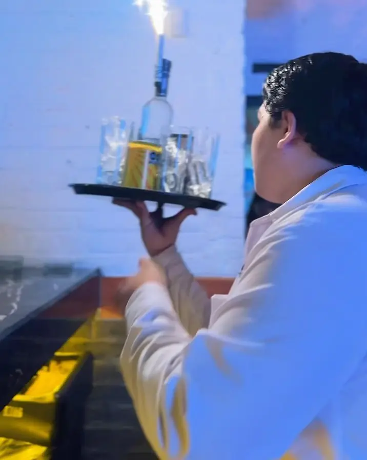 Mesero llevando botella con bengala